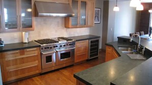 A modern kitchen with wooden cabinets, a stainless steel stove, and a large island with a sink. - Luxury ski-in townhome in Solitude Resort (Salt Lake City)