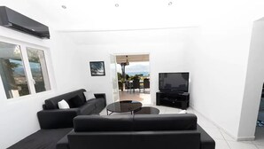 Un saló modern amb un sofà negre, una taula de centre i una televisió.
