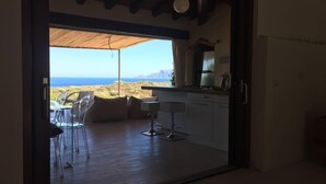 A modern kitchen with a view of the sea, a dining area with chairs, and a wooden floor. - Villa Smeraldo (Sottomonte)