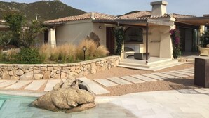 A house with a stone wall, a swimming pool, and a patio area. - Villa Smeraldo (Sottomonte)