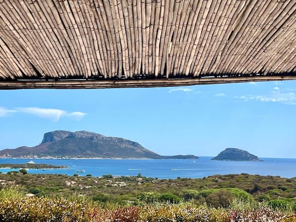 A coastal view with a mountain, a clear sky, and a wooden structure.