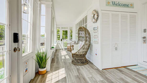 A bright hallway with a wicker chair, a welcome sign, and a view of the outdoors. - Ocean front and 3 beaches across,parks, short walk to historic downtown! (Gloucester)