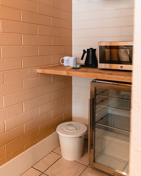 A compact kitchenette with a microwave, a coffee maker, and a small trash bin.