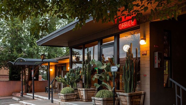 A building with a 'OFFICE' sign, wooden planters with cacti, and a staircase leading to the entrance.