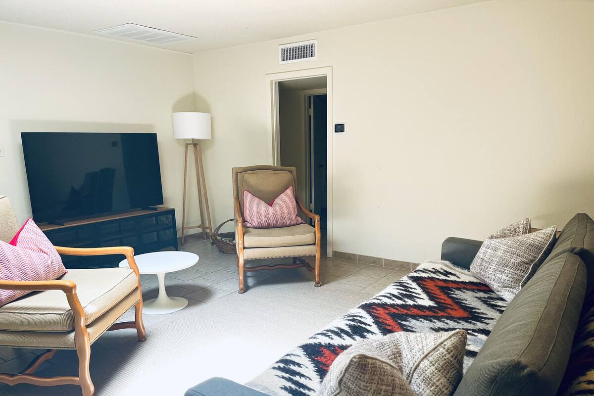 A living room with a sofa, armchairs, a TV, and a lamp.