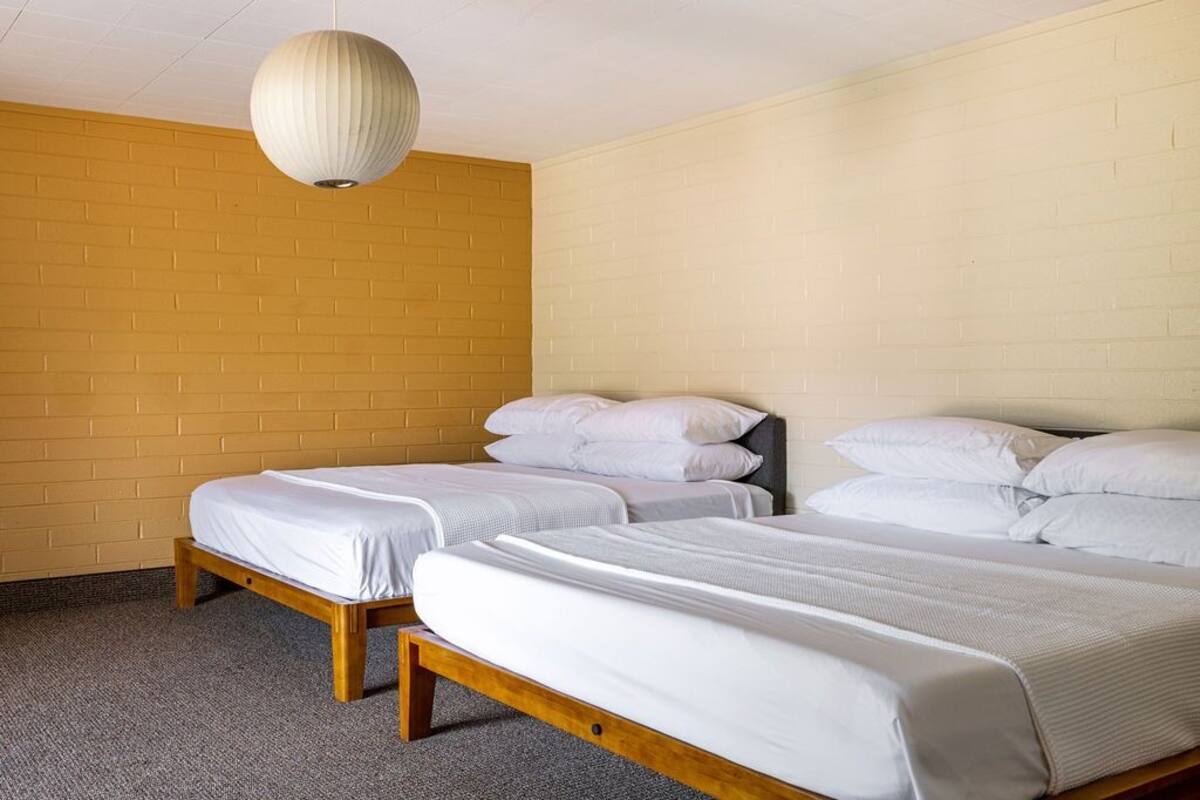 A room with two beds, a brick wall, and a hanging light fixture.