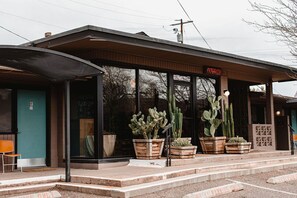 A building with a covered entrance, large windows, and potted cacti. - The Star Motel (Sedona)