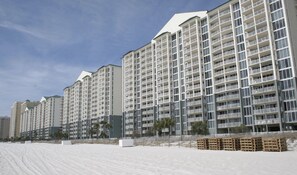 A beachfront hotel with multiple high-rise buildings, balconies, and a sandy beach area. - Long Beach Resort Tower 1-903 Free Beach Chairs & Umbrella Service! (Panama City Beach)