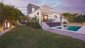 Een modern huis met een zwembad, terras en een verzorgd gazon.