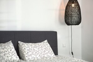 A bed with two pillows, a grey headboard, and a wall-mounted light fixture.