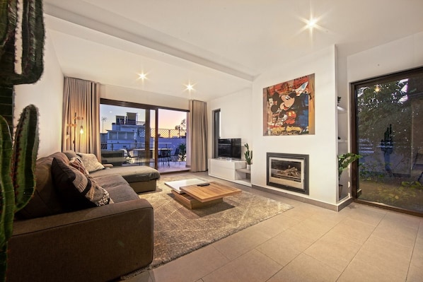 A modern living room with a sofa, coffee table, and fireplace. - Modern Villa close to Costabella beach (Marbella)