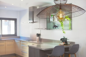 A modern kitchen with a central island, pendant lighting, and a view of the outdoors. - Modern Villa close to Costabella beach (Marbella)