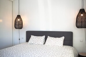 A bed with a grey headboard, two white pillows with a floral pattern, and a white bedspread.