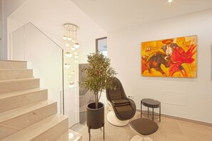 Ein modernes Interieur mit Treppe, Blumentopf, Liege und einem farbenfrohen Gemälde.