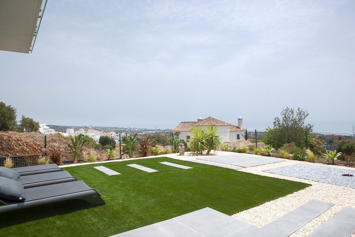A landscaped outdoor area with a lawn, seating area, and a view of a distant building.