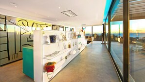 Un interior moderno con una exhibición de objetos decorativos, una pared de acento color turquesa y vistas a través de amplias ventanas.