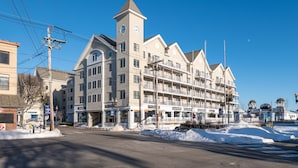 A multi-story hotel with a prominent clock tower, multiple balconies, and a variety of ground-level shops.
