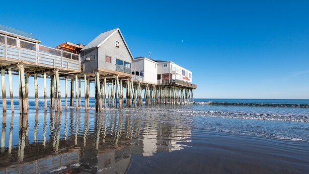 A wooden pier with a building extending over the water.