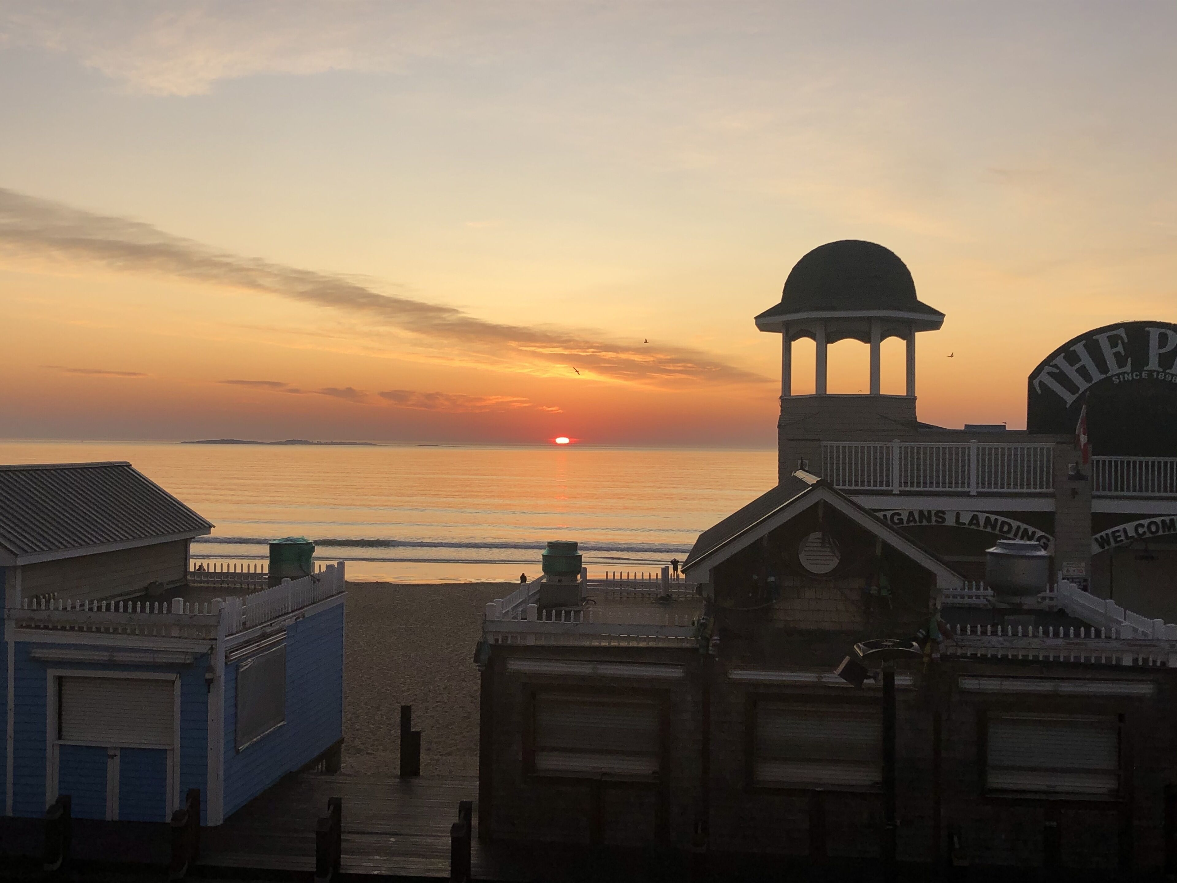 A beachside building with a dock, a bell tower, and a sign reading "The Pier".