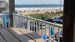 A beach view from a covered deck with a table and chairs, a gazebo, and a beach sign.