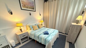 Et pænt indrettet hotelværelse med seng, sengeborde, lamper, kommode og et billede på væggen.