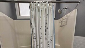 A shower area with a glass door, a bathtub, and a shower curtain with a floral pattern. - Beach, Boat Rentals, Near Horse Shows! RIverside Shores (Williamsburg)