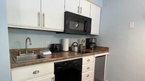 A compact kitchen with white cabinets, a black microwave, a sink, and a dishwasher. - Beach, Boat Rentals, Near Horse Shows! RIverside Shores (Williamsburg)