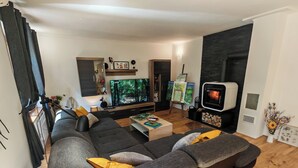 A modern living room with a large sectional sofa, a flat-screen TV, a fireplace, and a bookshelf. - Anemona House - Plitvice Lakes - 500 m  from  Big Waterfall (Plitvice Lakes)