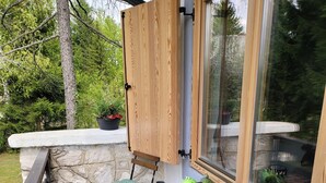 A wooden table with two chairs and a bench, a window with a wooden blind, and a stone wall. - Anemona House - Plitvice Lakes - 500 m  from  Big Waterfall (Plitvice Lakes)