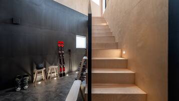 A modern interior with a staircase, wooden flooring, and ski equipment.