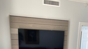 Un televisor de pantalla plana montado en una pared de madera con un estante debajo.