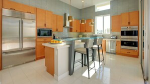 Una cucina moderna con elettrodomestici in acciaio inossidabile, mobili in legno e un'isola centrale con sgabelli da bar.