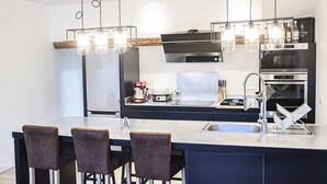A modern kitchen with a central island, stainless steel appliances, and pendant lighting. - Duplex Standing de 77m2 Avec Rooftop de vue mer Situé Plein Centre de Bandol (Bandol)