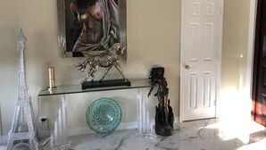 A marble foyer with a glass console table, a sculpture, a glass bowl, and a painting on the wall. - Hollywood Art Studio Apartment (Los Angeles)