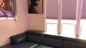 A living room with a dark green sectional sofa, a marble coffee table, and a wall-mounted air conditioner. - Hollywood Art Studio Apartment (Los Angeles)