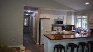 Una cocina moderna con armarios blancos, un refrigerador de acero inoxidable, un microondas e isla de madera con taburetes de bar.