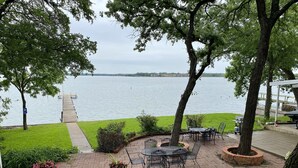 A patio area with outdoor seating, a view of the lake, and a dock extending into the water. - Cozy Lakefront Cottage on Eagle Mountain Lake (Azle)