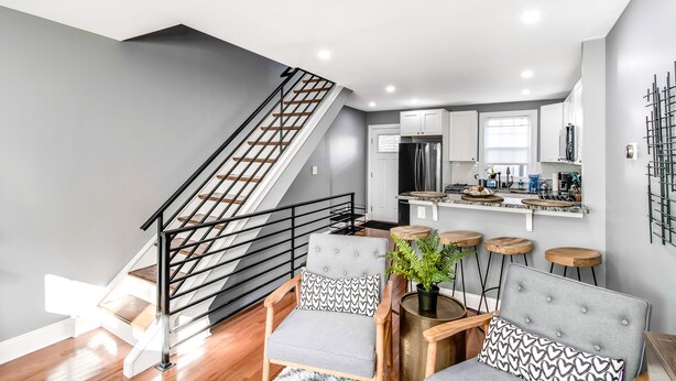 A modern kitchen with white cabinets, a stainless steel refrigerator, and a bar area with stools. - ★ Stunning 3BR Modern Charm in South Philly ★ (Philadelphia)