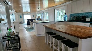 Una cocina moderna con armarios blancos, una encimera de madera y una barra con taburetes.