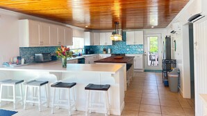 Una cocina moderna con armarios blancos, un salpicadero de azulejos azules y un techo de madera.