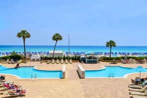 A pool area with multiple swimming pools, lounge chairs, and umbrellas.