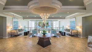 A spacious lobby with a central round table, seating area with sofas, and a chandelier.