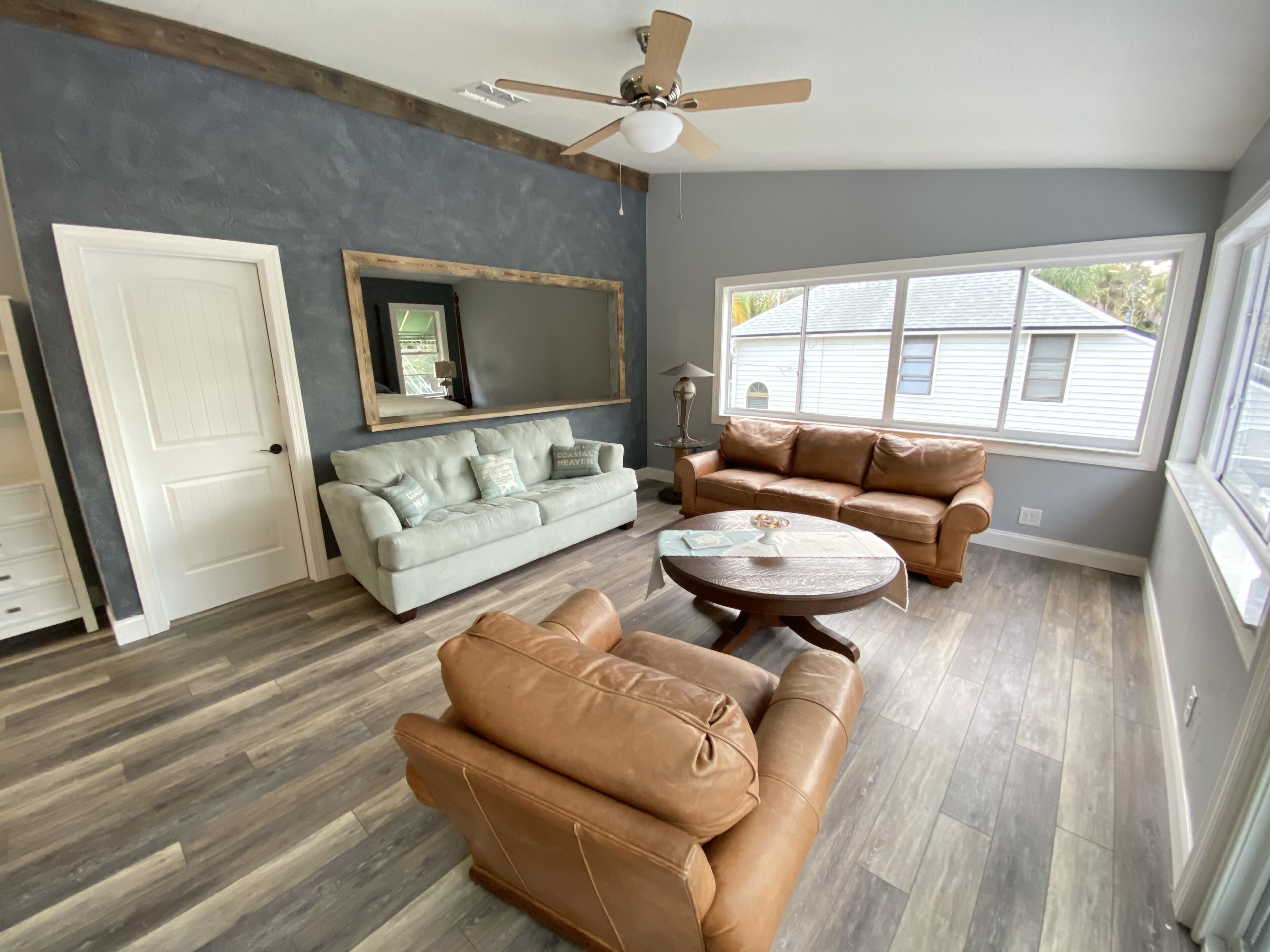 A living room with two sofas, a coffee table, a ceiling fan, and a large window.