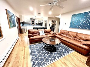 Ein Wohnzimmer mit einem braunen Leder-Modulsofa, einem runden Couchtisch und einem gemusterten Teppich.