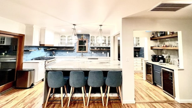 Una cocina moderna con una isla central, taburetes de bar y un horno empotrado.