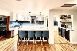 Una cucina moderna con isola centrale, sgabelli da bar e forno integrato.