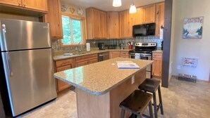 A kitchen with wooden cabinets, stainless steel appliances, granite countertops, and pendant lighting. - Cottonwood Chalet (Packwood)