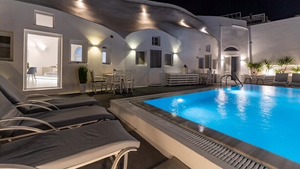 Et moderne poolområde med liggestole, en pool og en bygning med unik arkitektur.