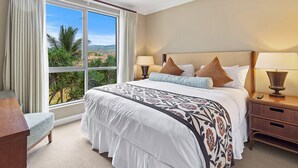 A hotel room with a large window, a bed with a patterned bedspread, two bedside lamps, and a nightstand with a remote control. - Maui Resort Rentals: Honua Kai - 4 Total Bedrooms, Gorgeous West Maui Mountain & Partial Ocean Views! (Lahaina)