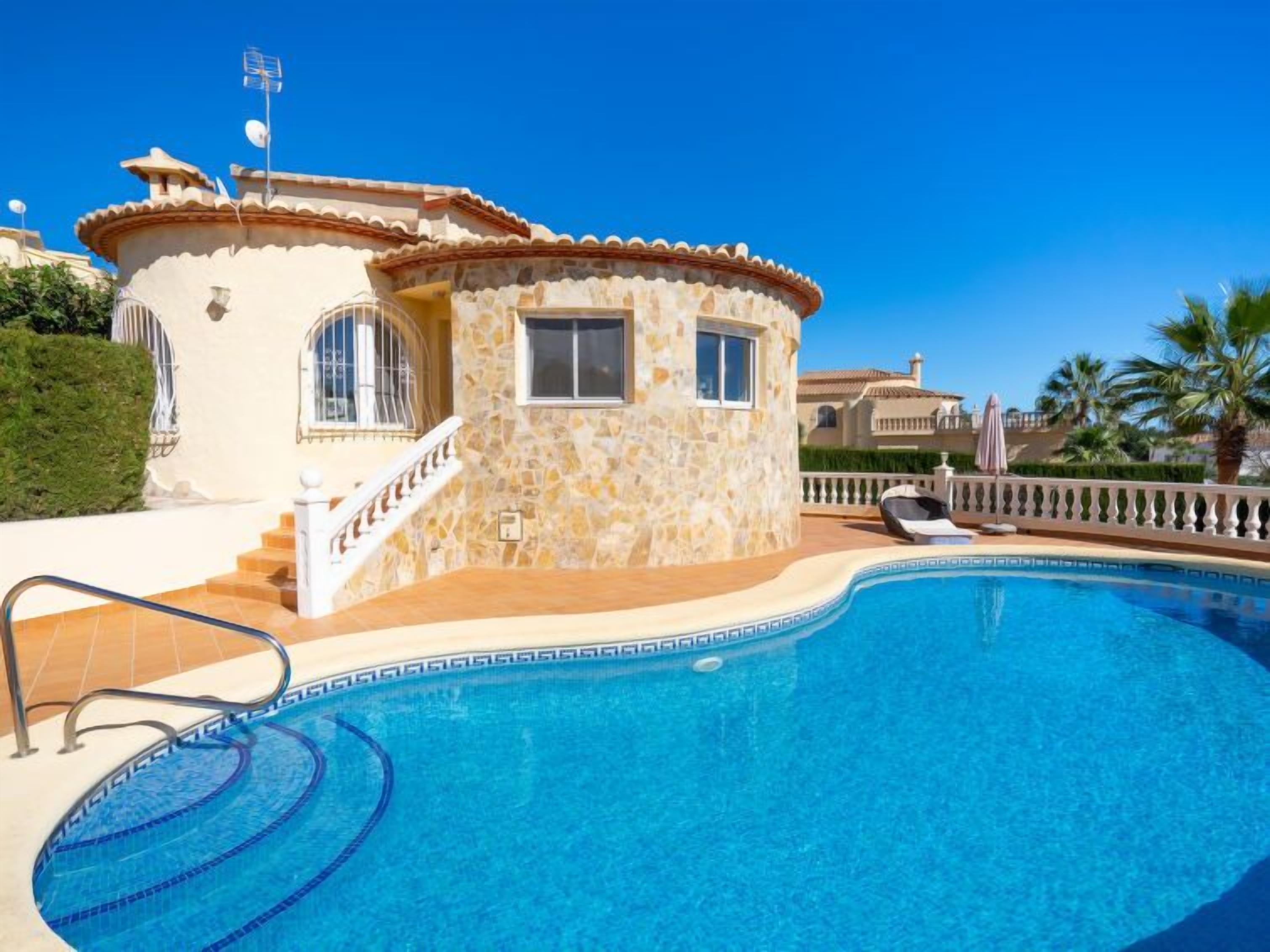 A stone building with a pool, a staircase, and a railing.